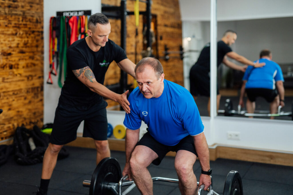 Personal Trainer hilft Klienten dabei, Deadlift-Übung richtig auszuführen.