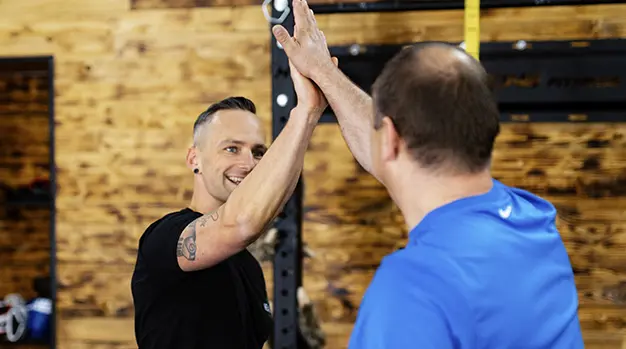 Marco Neumann gibt einem Kunden nach einem erfolgreichen Workout in Friedberg ein motivierendes High Five.