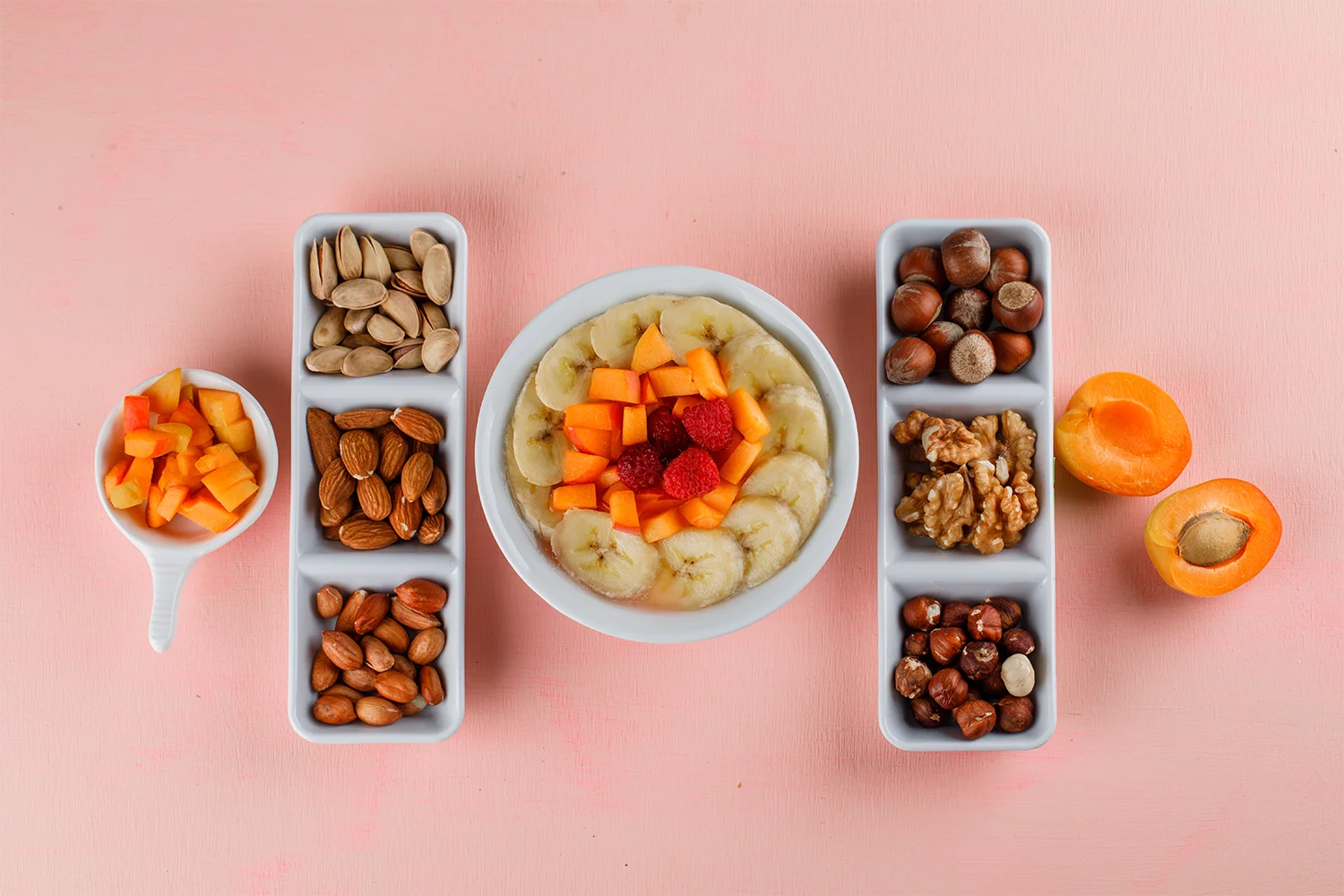 Frische Obststücke mit Banane, Beeren und Nüssen in Schalen – nährstoffreiche Lebensmittel für gesundes Altern
