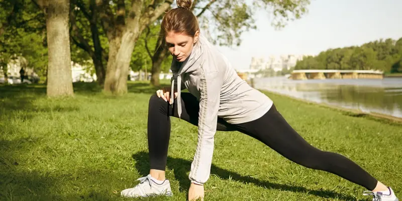 Frau dehnt sich im Park und macht Outdoor Training