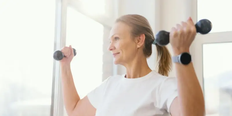 Frau mittleren Alters macht zuhause ein Workout um auch ab 40 fit zu bleiben.