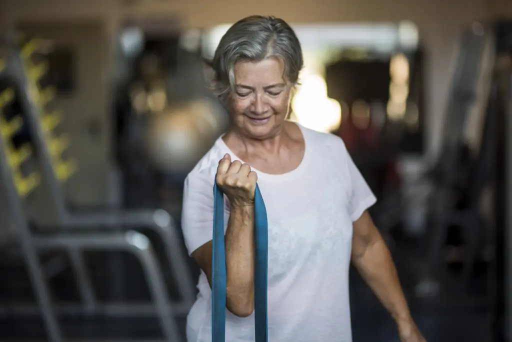 Seniorin führt eine Schulterübung mit dem Widerstandsband aus