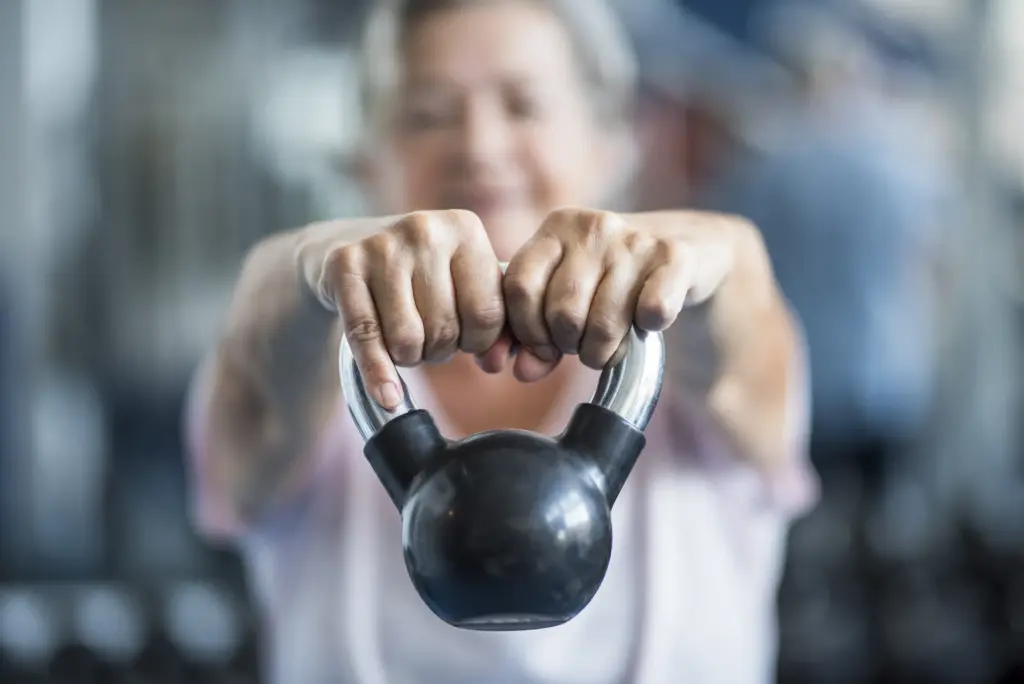 Frau hält eine Kettlebell mit beiden Händen vor dem Körper im Training