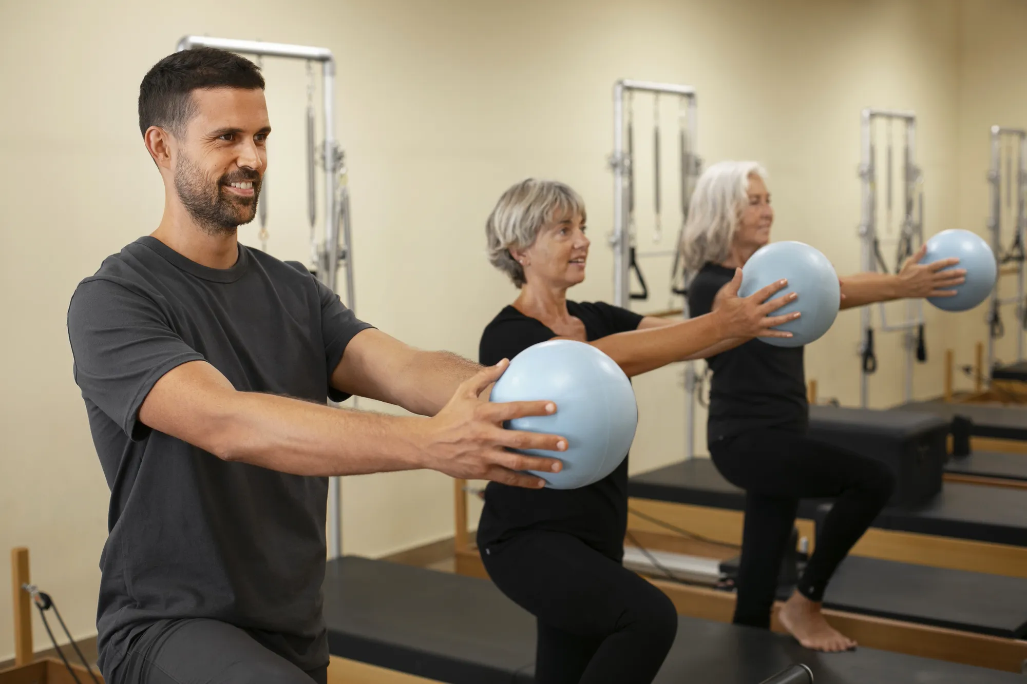 Trainer und Seniorinnen trainieren mit Pilatesbällen in der Kniebeuge