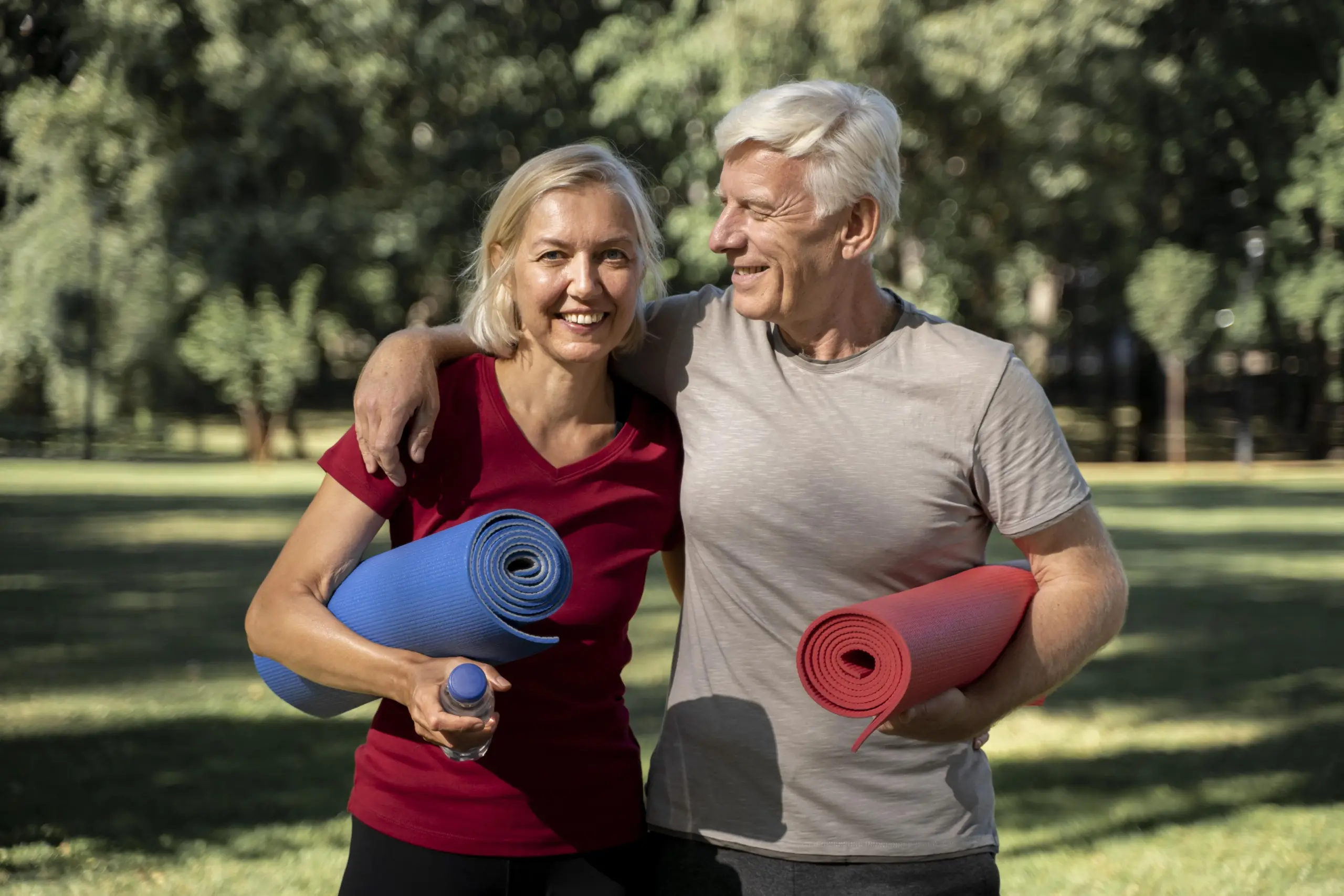 Rehasport Augsburg 4 Lächelndes älteres Paar mit Yogamatten im Park