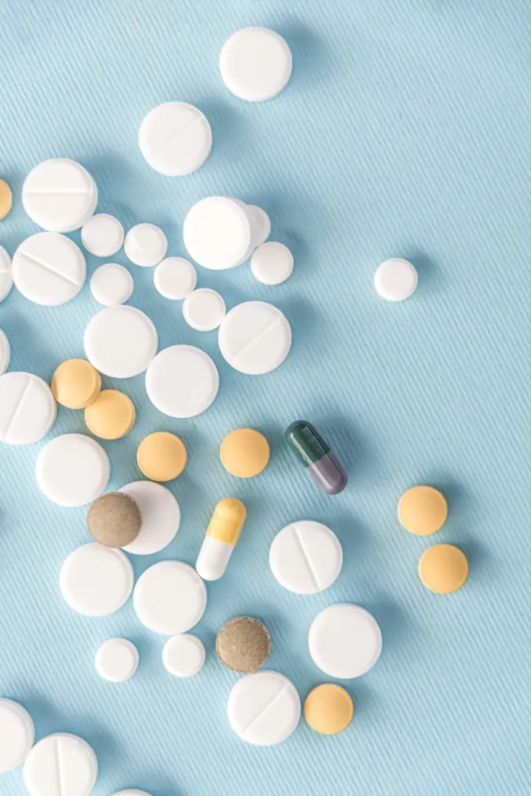 Gesund und nachhaltig abnehmen 4 Verschiedene Tabletten und Kapseln auf hellblauem Untergrund