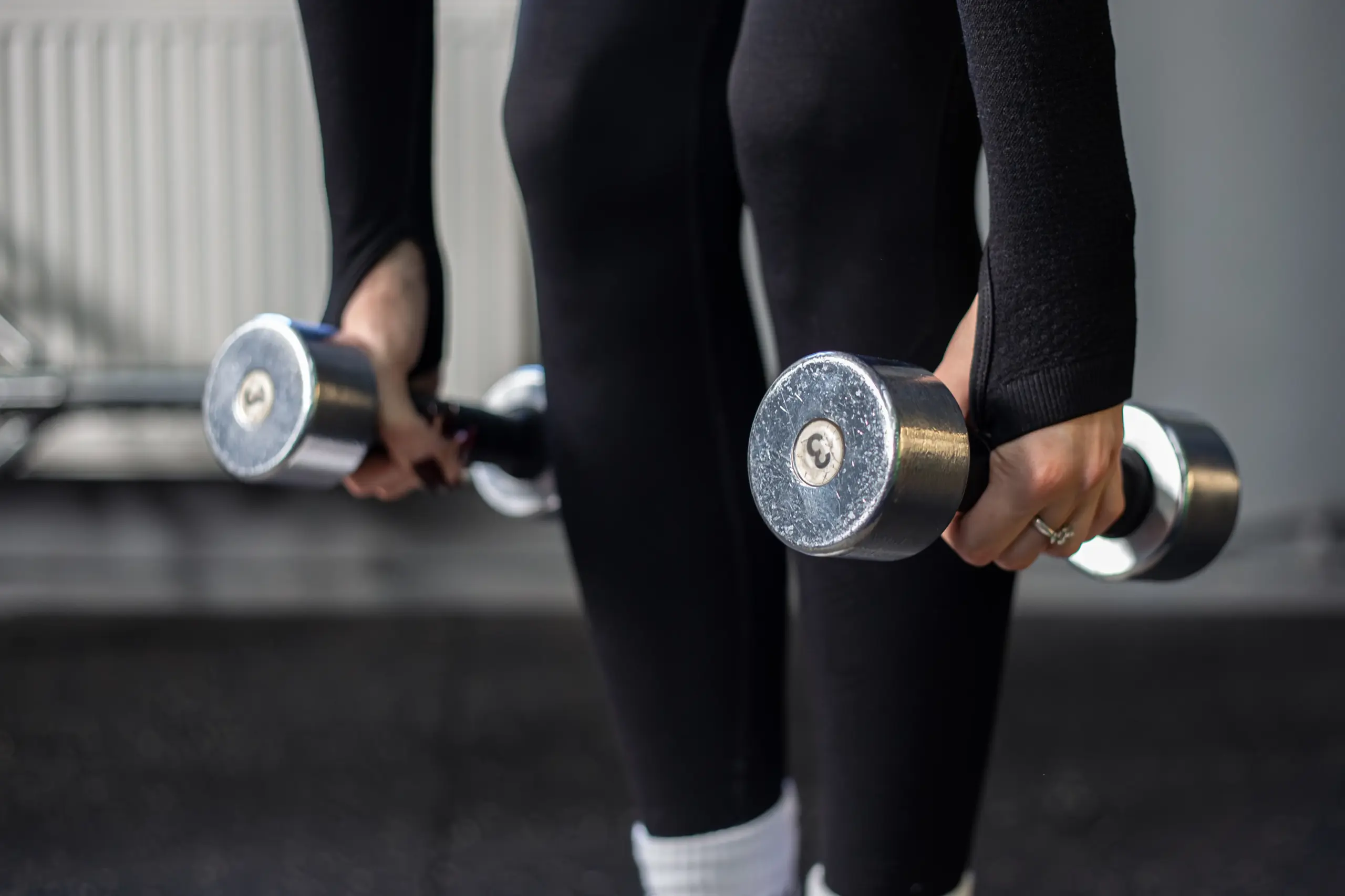 Mehr Beweglichkeit und Ausdauer 3 Nahaufnahme zweier Kurzhanteln in den Händen einer Frau beim Krafttraining